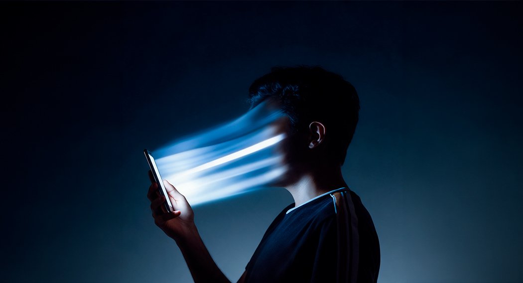 Um homem absorto olhando para um tablet iluminado, simbolizando desejo e engajamento